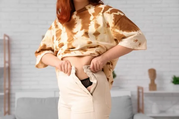 Image of woman trying to do her trousers up after pregnancy weight gain Newark on Trent