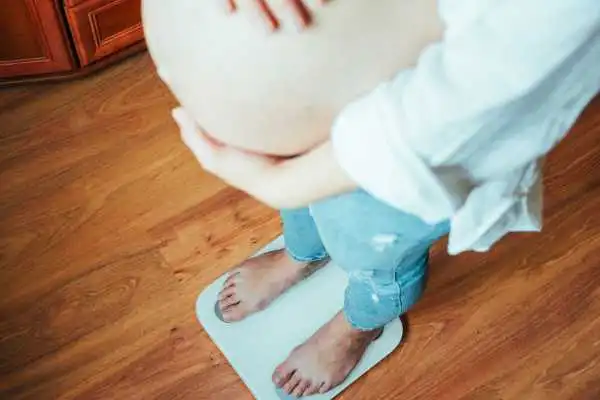 Image of woman weighing herself and experiencing weight gain through pregnancy Newark on Trent